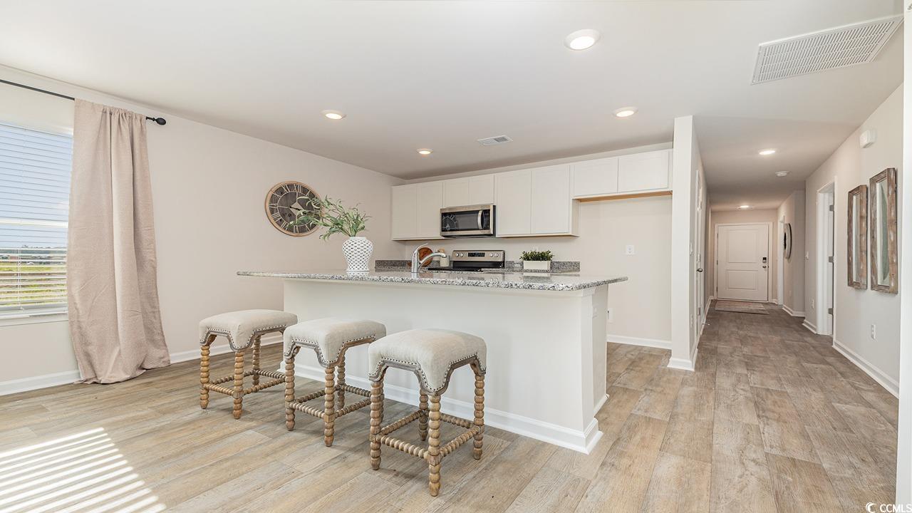 1019 St Martin Street Georgetown, SC 29440 - Photo 11 of 33 Kitchen featuring recessed lighting, light stone countertops, white cabinets, stainless steel appliances, and an island with sink
