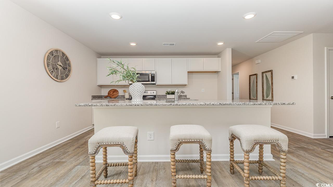 1019 St Martin Street Georgetown, SC 29440 - Photo 12 of 33 Kitchen with recessed lighting, light stone countertops, white cabinetry, a center island with sink, and light wood-type flooring
