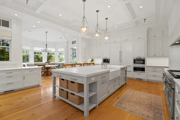 a large white kitchen with a large window a island a stove and a wooden floors