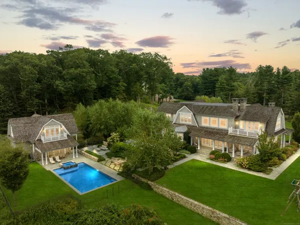 an aerial view of a house with pool big yard and large trees