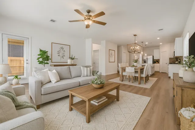 a living room with furniture kitchen view and a chandelier