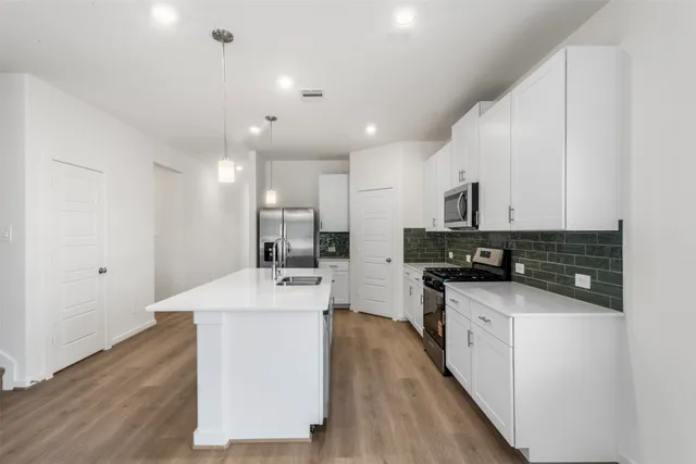 a large white kitchen with wooden floor