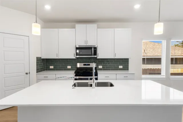 a kitchen with stainless steel appliances a stove a microwave and white cabinets