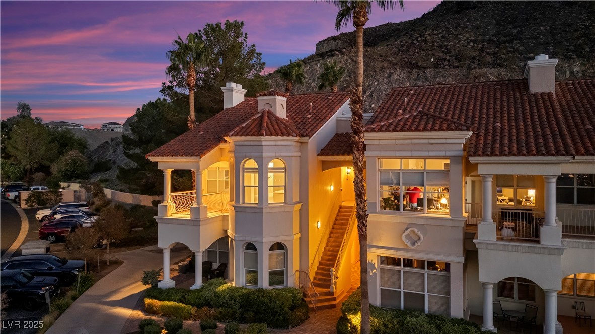 Mediterranean / spanish-style house with stucco siding, a chimney, stairway, and a balcony