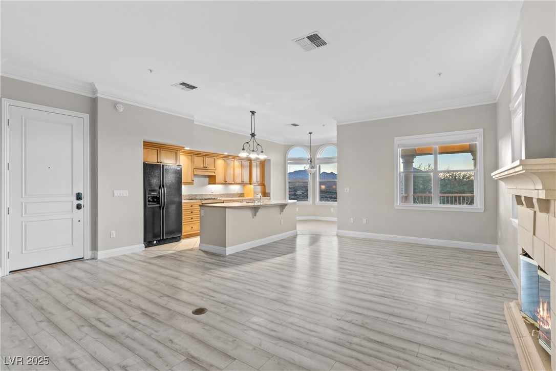 35 Strada Di Circolo Henderson, NV 89011 - Photo 11 of 28 Unfurnished living room featuring ornamental molding, a glass covered fireplace, light wood-type flooring, and a chandelier