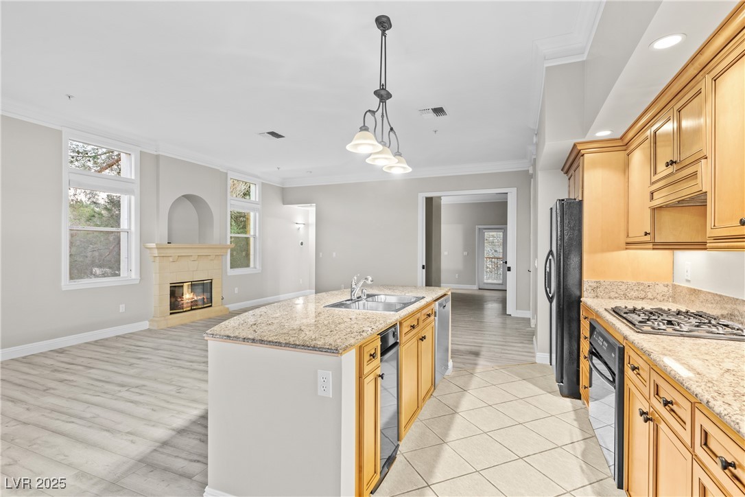 35 Strada Di Circolo Henderson, NV 89011 - Photo 27 of 28 Kitchen featuring ornamental molding, decorative light fixtures, open floor plan, light stone counters, and a tile fireplace
