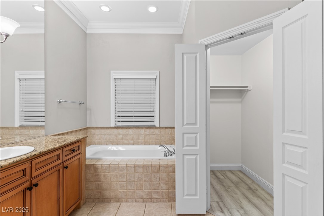35 Strada Di Circolo Henderson, NV 89011 - Photo 18 of 28 Full bath featuring crown molding, a bath, vanity, a spacious closet, and light tile patterned flooring
