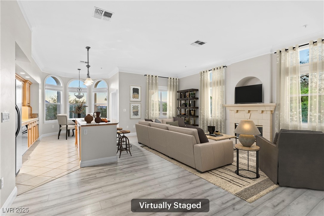 35 Strada Di Circolo Henderson, NV 89011 - Photo 6 of 28 Living area with crown molding, a tiled fireplace, a chandelier, and light wood finished floors