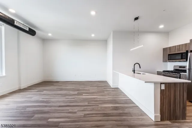 a view of a kitchen with kitchen island stainless steel appliances counter space and wooden floor