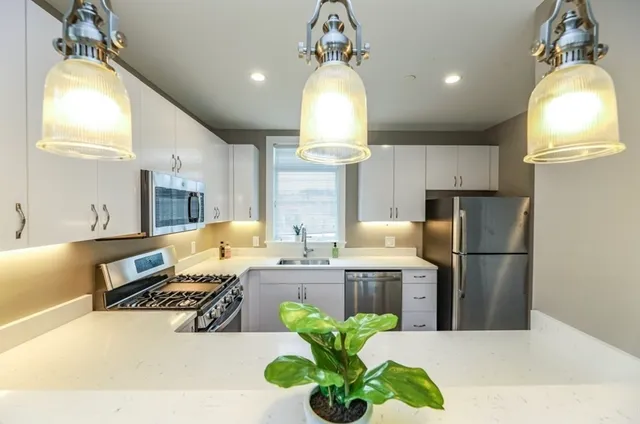 a kitchen with kitchen island granite countertop a stove a sink a refrigerator and a dining table