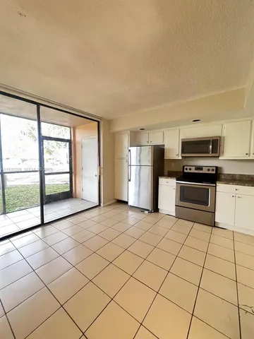 a large white kitchen with a stove a sink dishwasher and a refrigerator with wooden floor