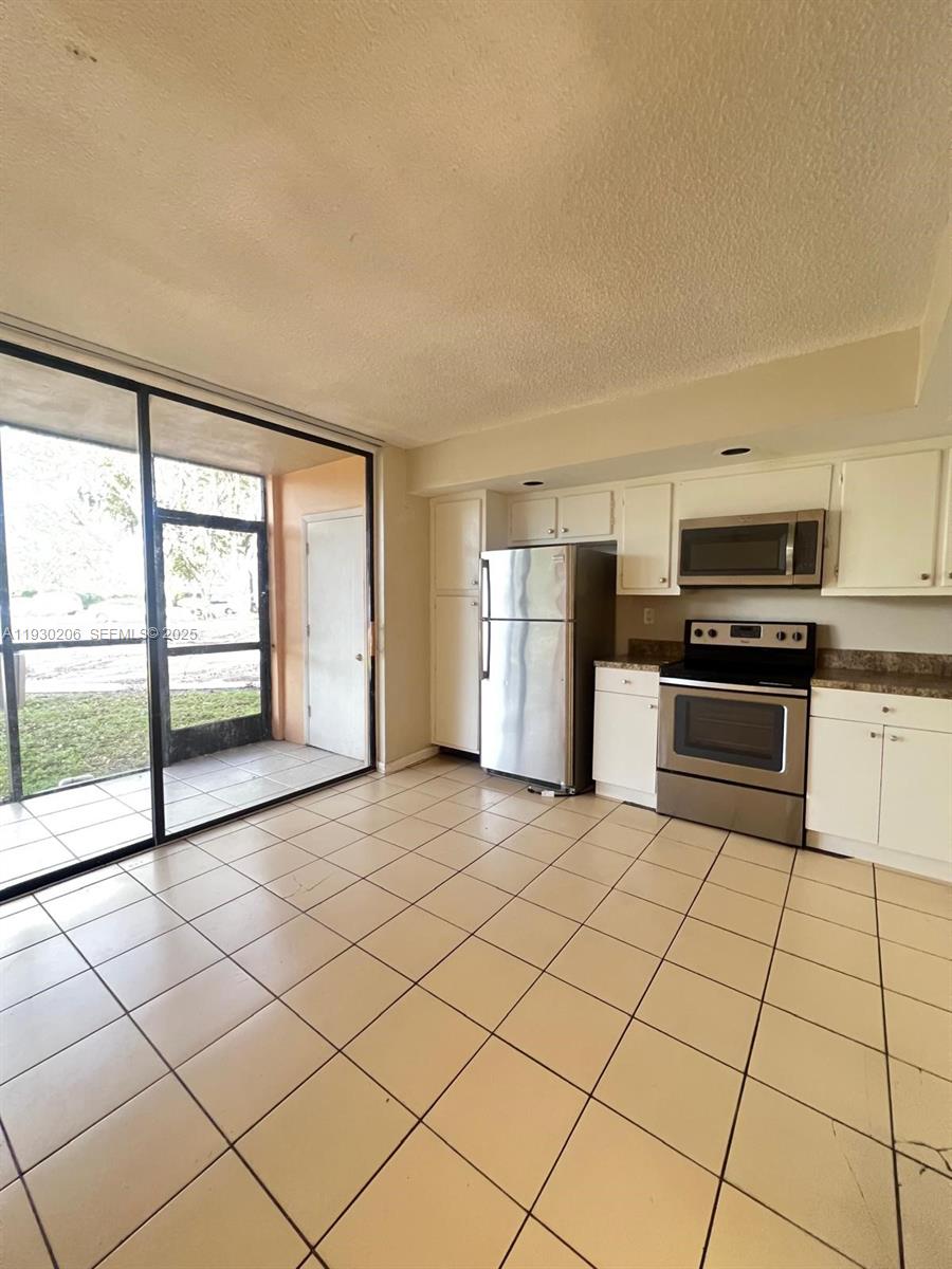 a large white kitchen with a stove a sink dishwasher and a refrigerator with wooden floor