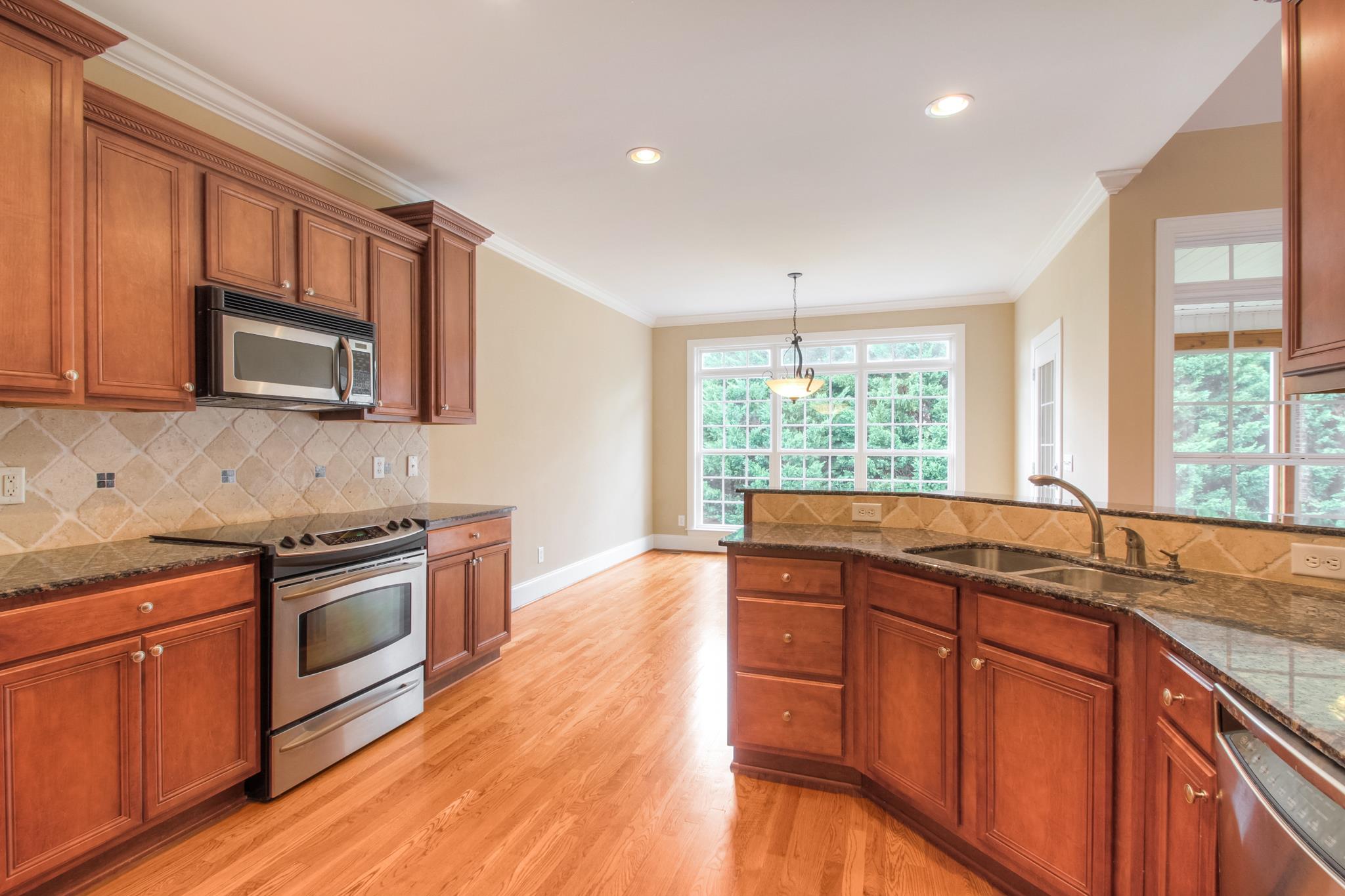 1631 Fair House Road Spring Hill, TN 37174 - Photo 12 of 29 a kitchen with stainless steel appliances granite countertop wooden floors and white cabinets