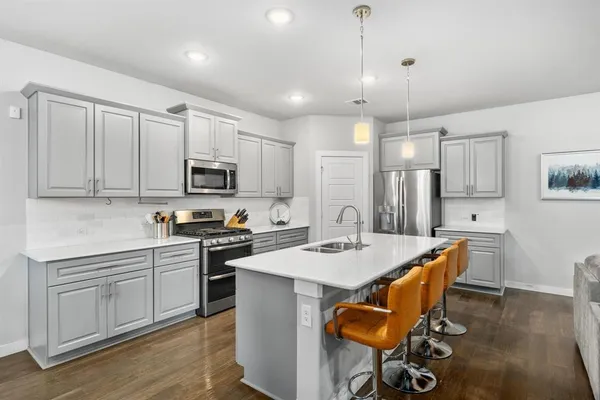 a kitchen with stainless steel appliances kitchen island granite countertop a sink a stove a dining table and chairs