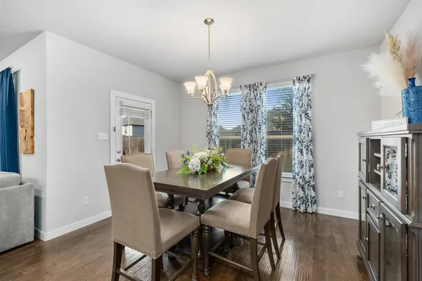 a dining room with furniture a chandelier and wooden floor