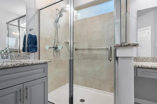 a bathroom with a granite countertop shower sink vanity and mirror