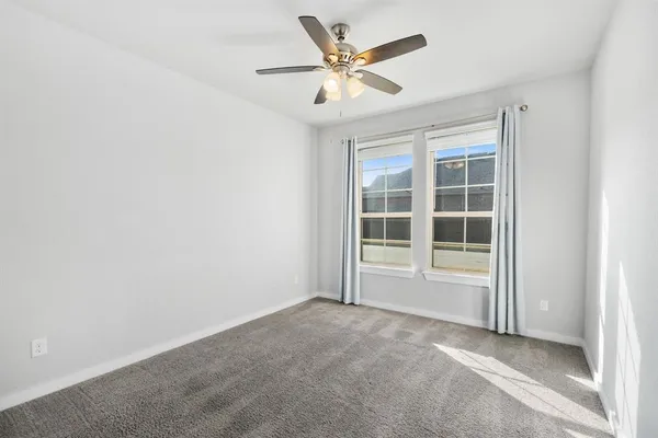 an empty room with windows and ceiling fan