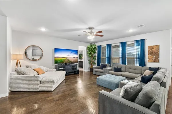 a living room with furniture ceiling fan and a large window