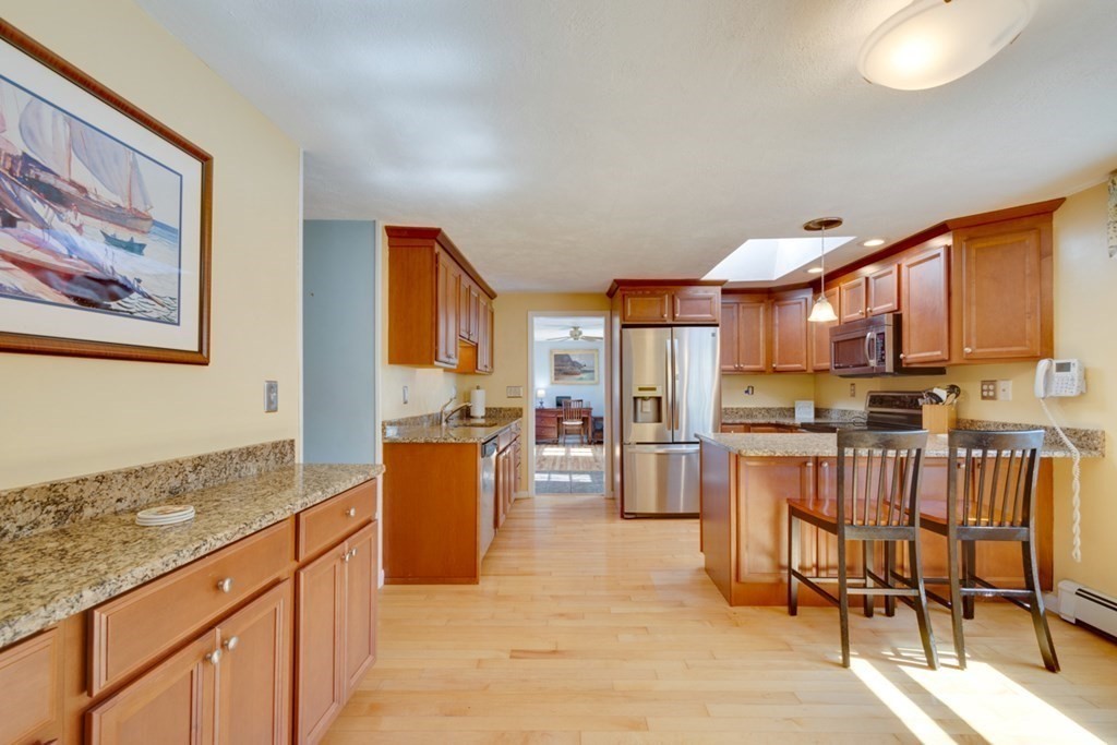 29 Anna Road Woburn, MA 01801 - Photo 4 of 29 a kitchen with stainless steel appliances kitchen island granite countertop a refrigerator a stove top oven and a dining table with wooden floor