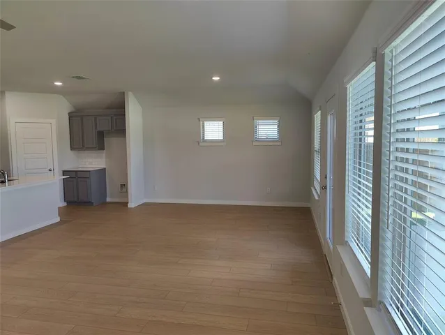 a view of empty room with kitchen and window