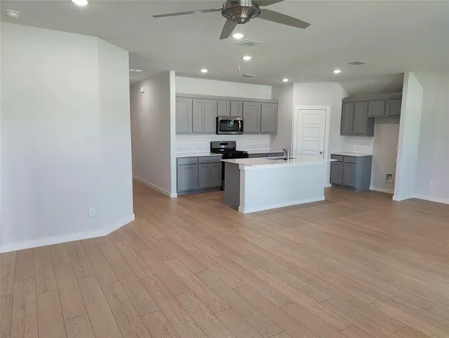 a large kitchen with stainless steel appliances a large counter top a sink a refrigerator and a stove