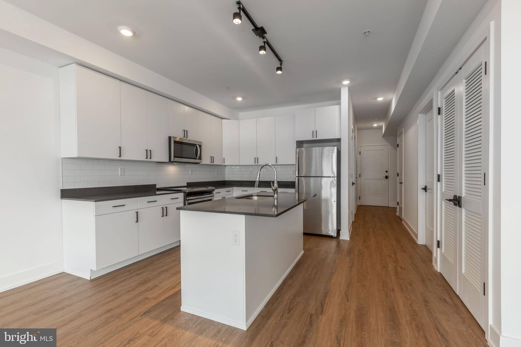 1519 Ridge Avenue, Unit 503 Philadelphia, PA 19130 - Photo 30 of 40 a kitchen with stainless steel appliances granite countertop a refrigerator a stove a sink and white cabinets with wooden floor