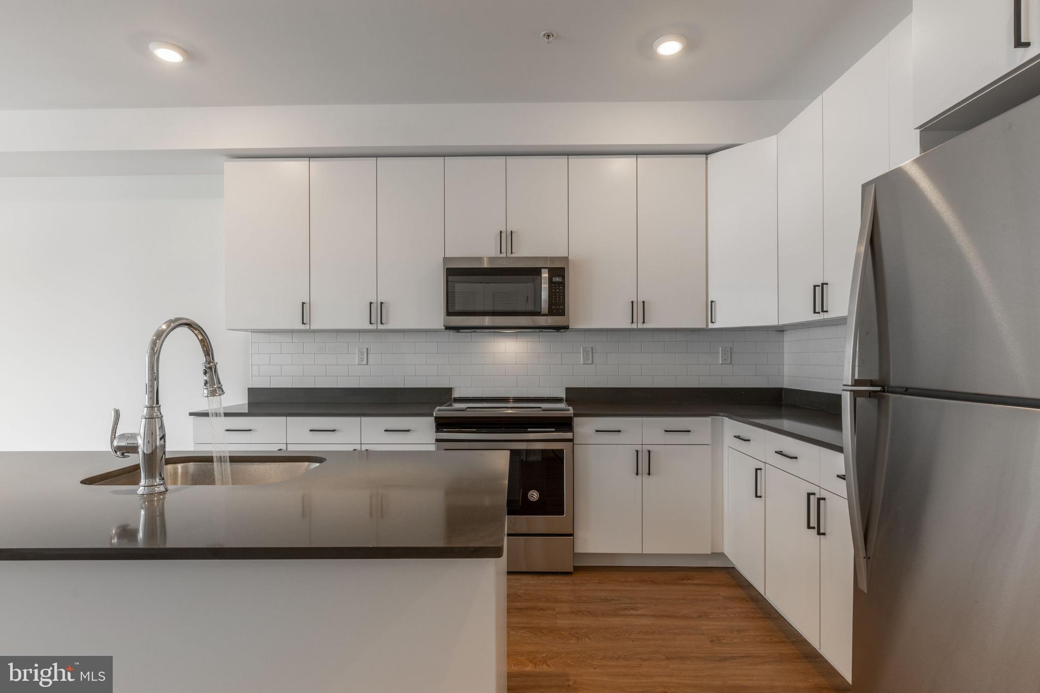 1519 Ridge Avenue, Unit 503 Philadelphia, PA 19130 - Photo 33 of 40 a kitchen with stainless steel appliances a stove a sink and white cabinets