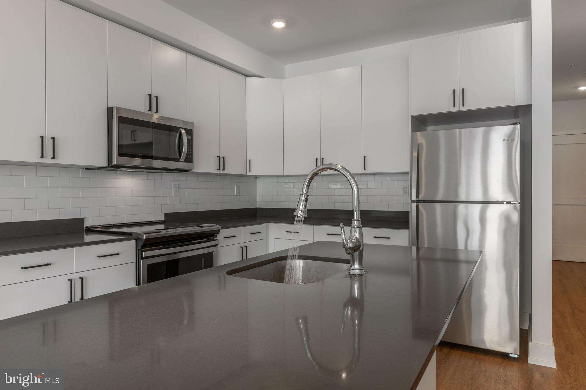 1519 Ridge Avenue, Unit 503 Philadelphia, PA 19130 - Photo 34 of 40 a kitchen with stainless steel appliances granite countertop a refrigerator a sink a stove and white cabinets