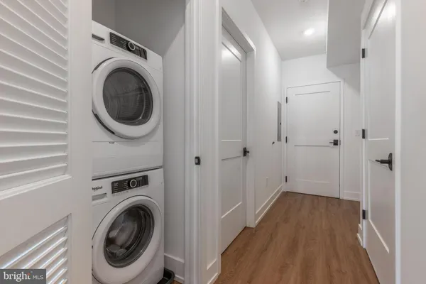 a view of a hallway with wooden floor and a bathroom