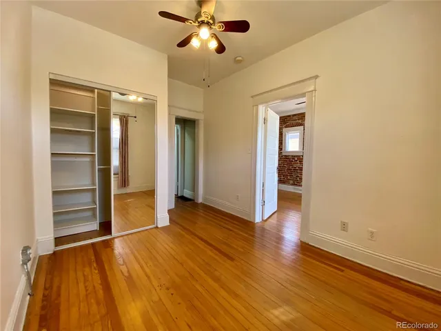 an empty room with wooden floor closet and windows