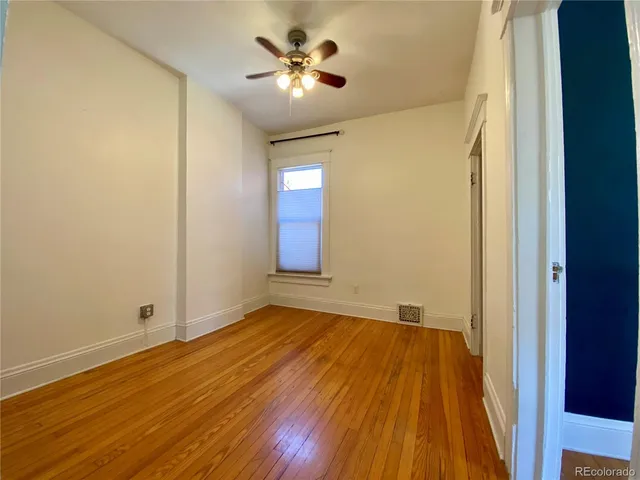 a view of empty room with wooden floor and fan