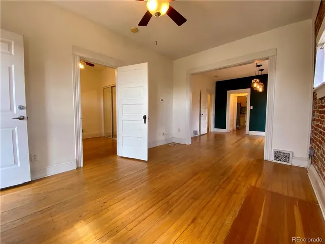 a view of a room with wooden floor a ceiling fan