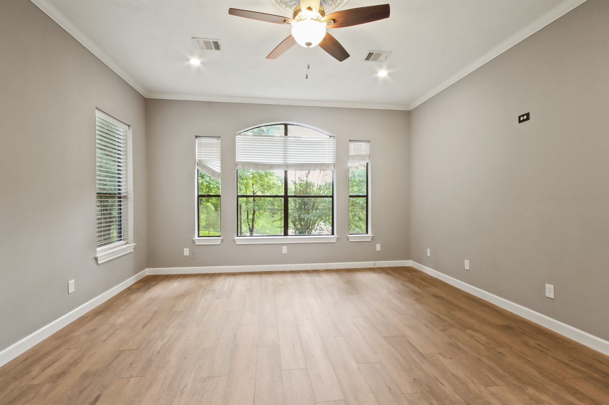 35 Susan Drive Cleveland, TX 77327 - Photo 9 of 33 Bright and spacious room with light wood flooring, neutral walls, and large windows offering scenic views. Features a ceiling fan and recessed lighting, creating a modern and welcoming atmosphere.
