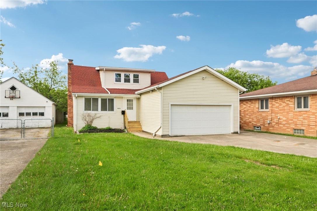 View of front of house with entry steps, a chimney, an attached garage, and an outbuilding