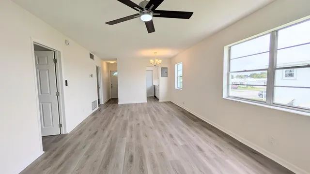 a view of empty room with wooden floor and fan