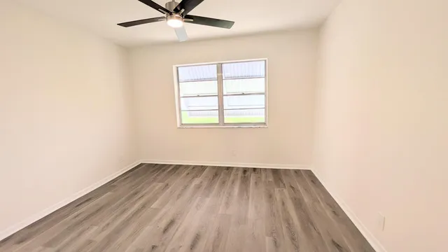 an empty room with a window and a fan