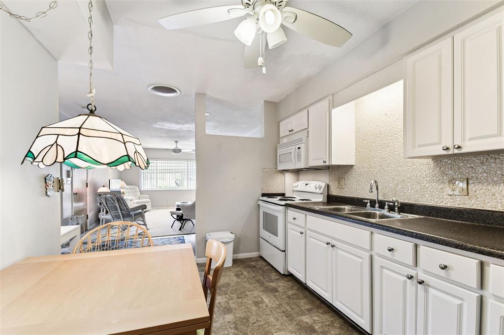 250 Rosery Road Northwest, Unit 333 Largo, FL 33770 - Photo 24 of 63 a kitchen with stainless steel appliances a white cabinets wooden floors and a chandelier