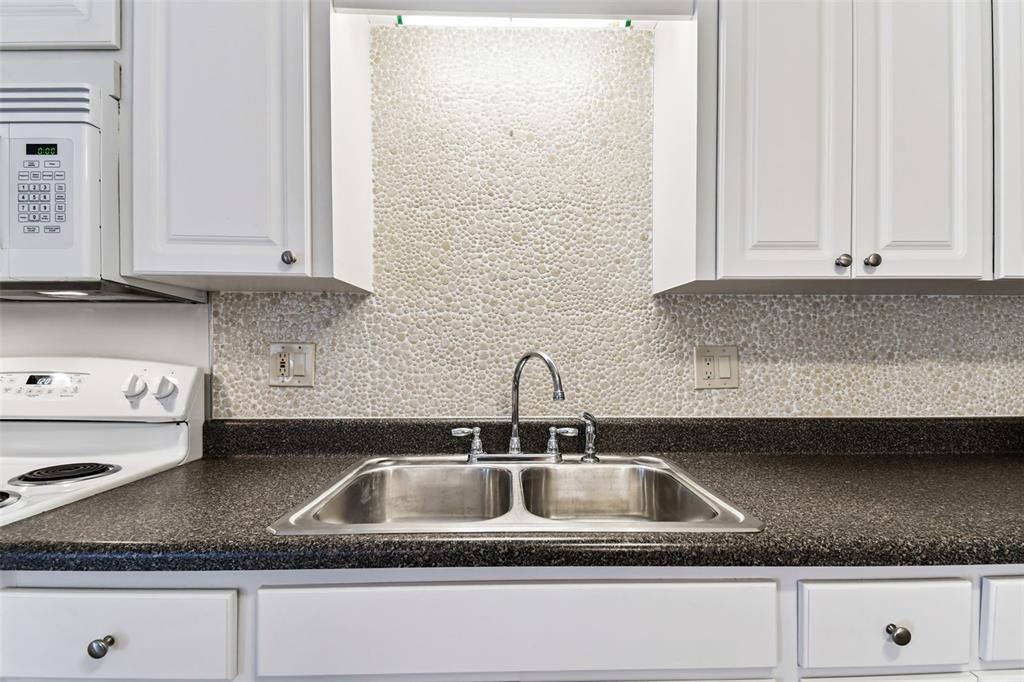 250 Rosery Road Northwest, Unit 333 Largo, FL 33770 - Photo 26 of 63 a kitchen with granite countertop a sink and a white cabinets