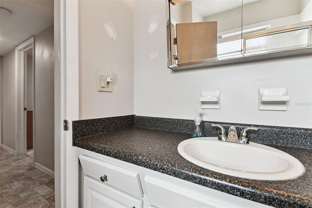250 Rosery Road Northwest, Unit 333 Largo, FL 33770 - Photo 29 of 63 a bathroom with a granite countertop sink and a mirror