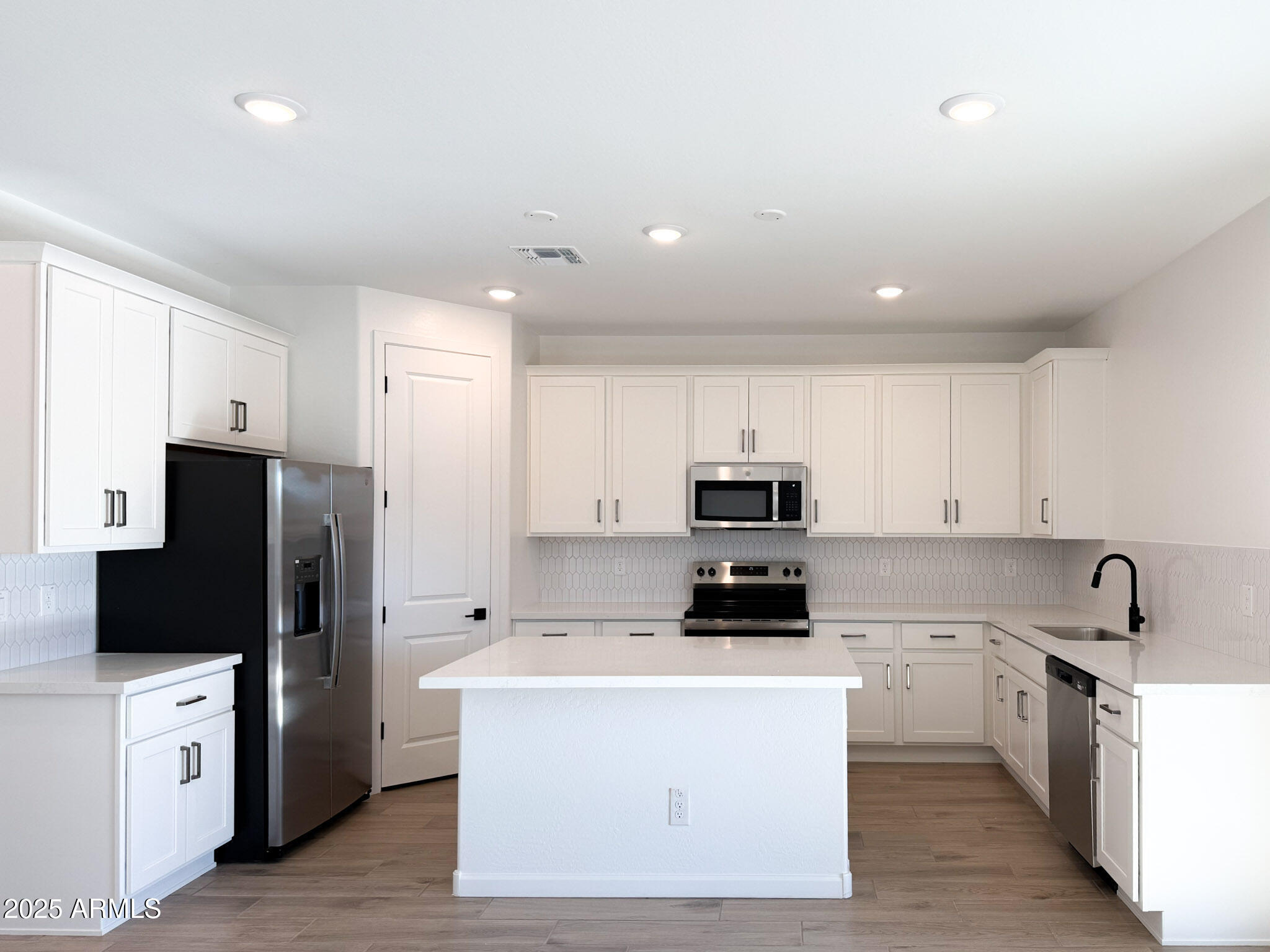 18203 La Senda Drive West Surprise, AZ 85387 - Photo 3 of 43 a kitchen with stainless steel appliances a refrigerator stove a sink and white cabinets