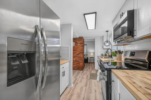 a kitchen with a sink and a stove with wooden floor