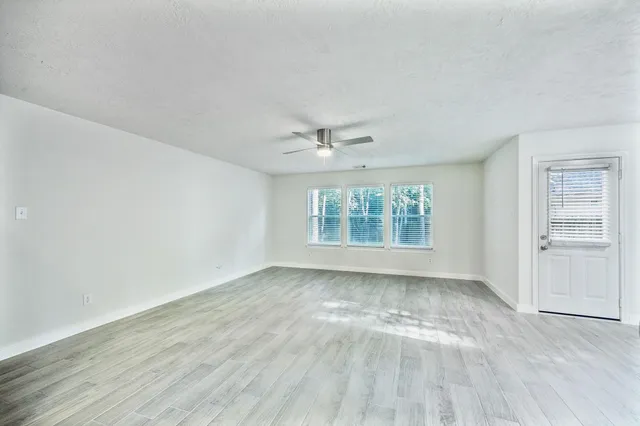 a view of an empty room with a window and wooden floor