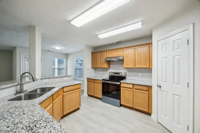 a kitchen with stainless steel appliances granite countertop a sink stove and cabinets