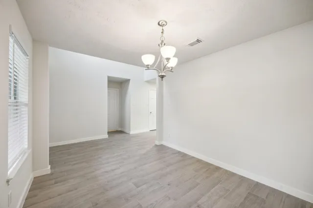 a view of a chandelier in big room with wooden floor
