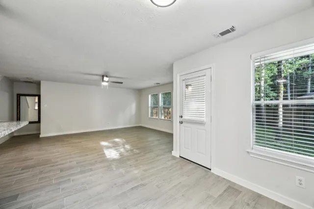 a view of an empty room with wooden floor and a window