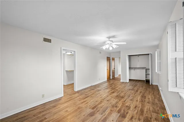 a view of empty room with wooden floor and fan