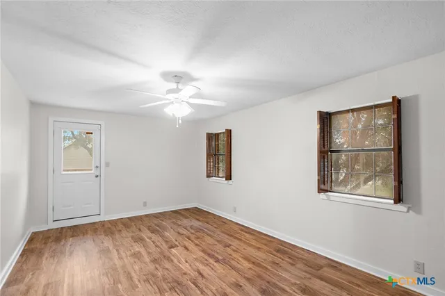 a view of empty room with wooden floor and fan