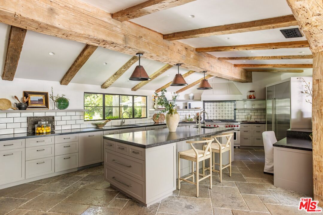 3099 Mandeville Canyon Road Los Angeles, CA 90049 - Photo 14 of 50 a kitchen with lots of counter top space and painting on the wall