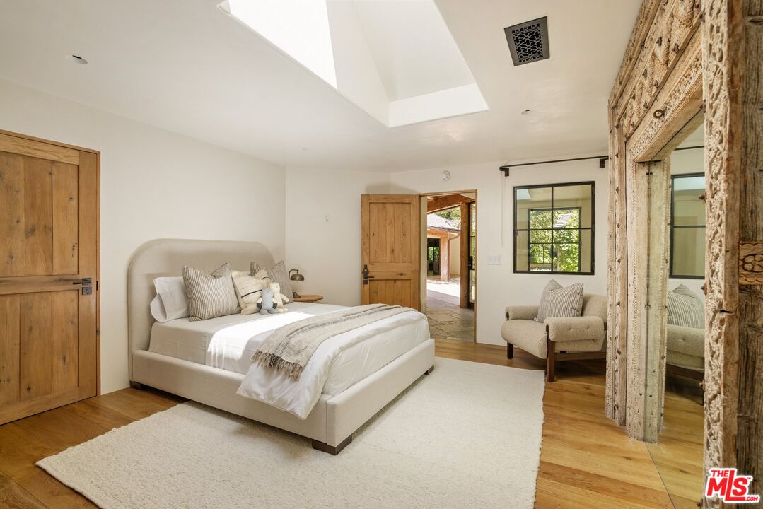 3099 Mandeville Canyon Road Los Angeles, CA 90049 - Photo 33 of 50 a bedroom with a bed wooden floor and next to a window