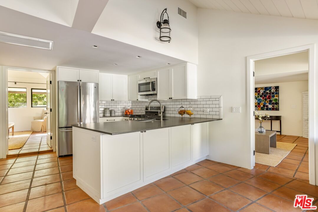 3099 Mandeville Canyon Road Los Angeles, CA 90049 - Photo 40 of 50 a kitchen with granite countertop a refrigerator and a stove top oven